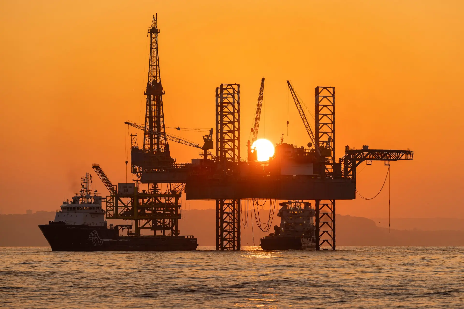 Gün batımında açık denizde doğalgaz platformu ve destek gemileri